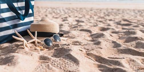 Sac, chapeau de paille, lunettes de soleil posés sur le sable d'une plage