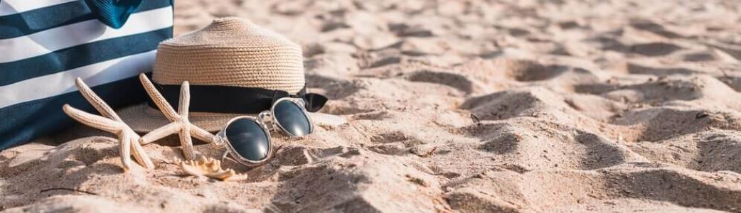 Sac, chapeau de paille, lunettes de soleil posés sur le sable d'une plage