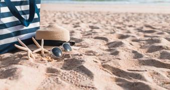 Sac, chapeau de paille, lunettes de soleil posés sur le sable d'une plage
