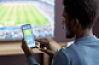 Jeune sur son téléphone devant un match